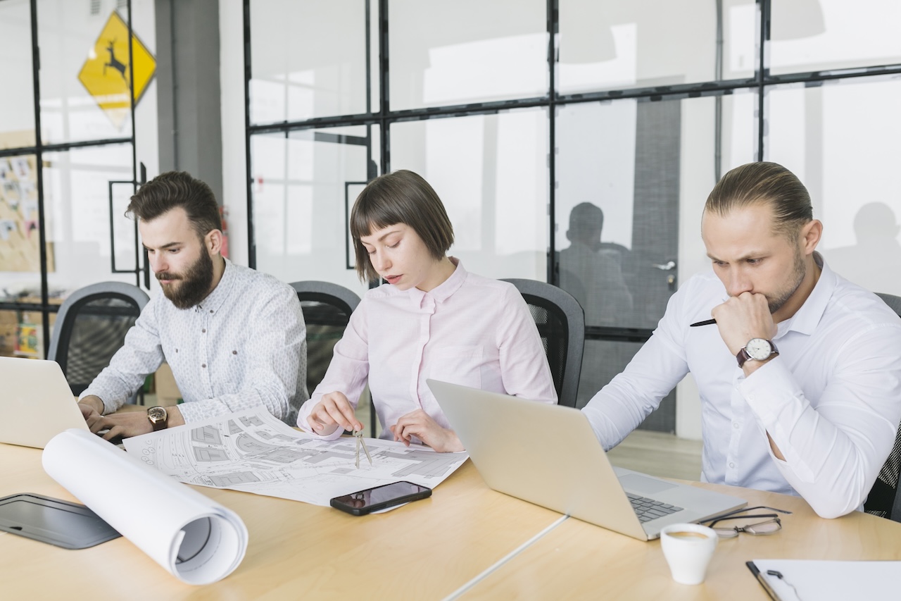 eam tecnico che analizza un progetto BIM su carta e laptop, durante una sessione di lavoro collaborativo legata alla certificazione SGBIM